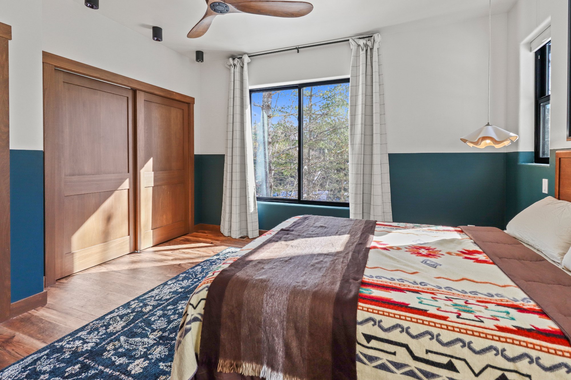 Primary bedroom queen teal wainscoting forest view