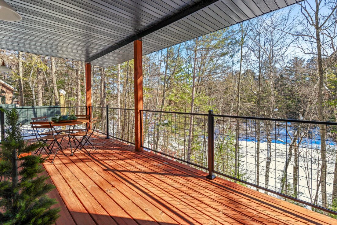 Covered deck dining area overlooking the woods and water