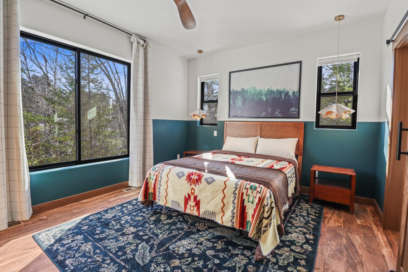 Primary bedroom with queen bed and forest views